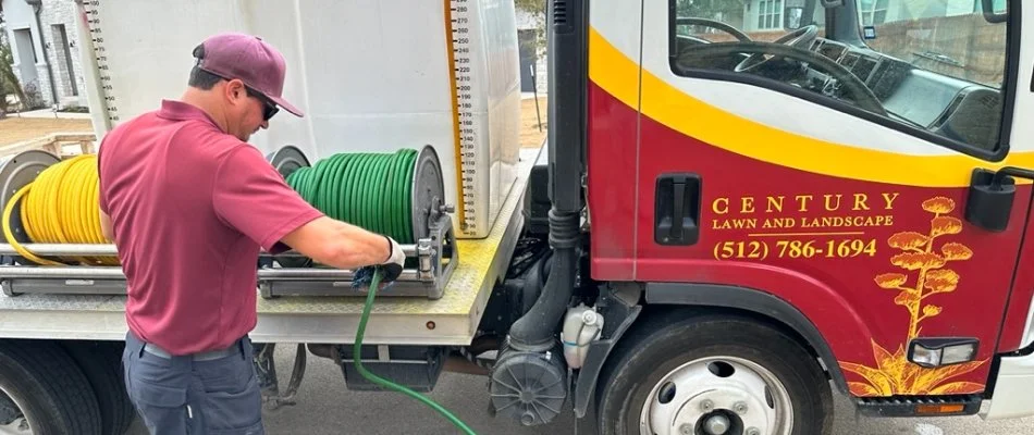 Lawn care employee rolling up hose on a truck at a house in Austin, TX.